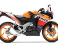 Pomarańczowo-czarny motocykl Honda CBR 125R w barwach Repsol, gotowy do wyścigów.