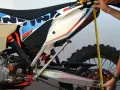 Mierzenie preload w amortyzatorze motocykla KTM 500 EXC. Dłoń trzyma miarkę przy tylnym kole.