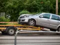 Srebrny samochód po wypadku, bez prawa rejestracji, ładowany na lawetę.