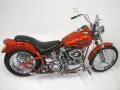 Pomarańczowy motocykl Harley-Davidson z silnikiem panhead, błyszczący chrom i płomienie na baku.