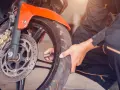 Mechanik sprawdza ciśnienie w oponie motocykla. Dowiedz się, jaka jest wymiana opon motocyklowych cena.