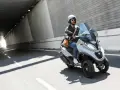 Mężczyzna w kasku jedzie skuterem 3 kołowym na kat B przez tunel.