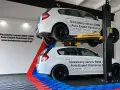 Dwa białe BMW, jedno na podnośniku, w serwisie Auto Expert. W tle logo BMW.