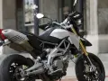 Srebrno-czarny motocykl Aprilia Dorsoduro 750 z żółtymi amortyzatorami, gotowy do jazdy po miejskich ulicach.