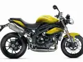 Żółty motocykl Triumph Speed Triple 1050 z czarnymi felgami i wydechem.