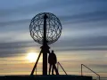 Sylwetka człowieka przy globusie na Nordkapp podczas zachodu słońca.