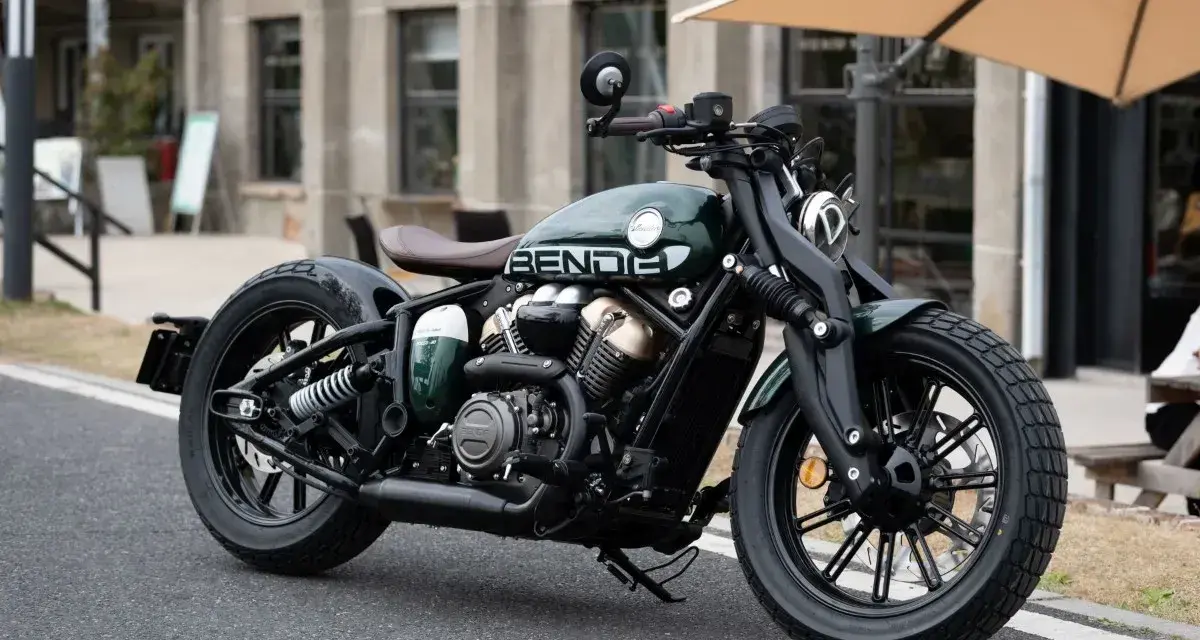 Stylowy, zielony motocykl typu cruiser z brązowym siedzeniem. Idealny do miejskich podróży, mógłby znaleźć się w rankingu motocykli cruiser.