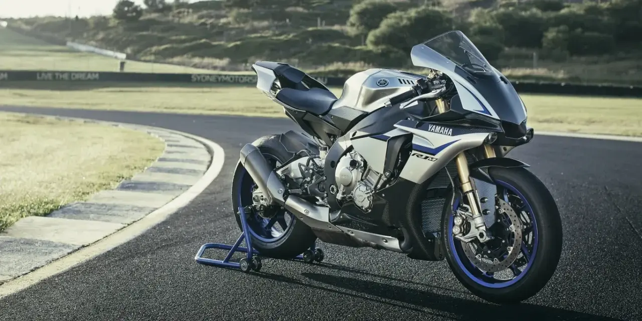 Srebrno-niebieski motocykl Yamaha R1M na torze wyścigowym, gotowy do jazdy.