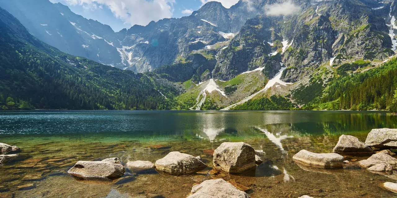 Kamienista droga na Morskie Oko prowadzi przez malownicze Tatry. Jezioro odbija skaliste szczyty i zielone lasy.