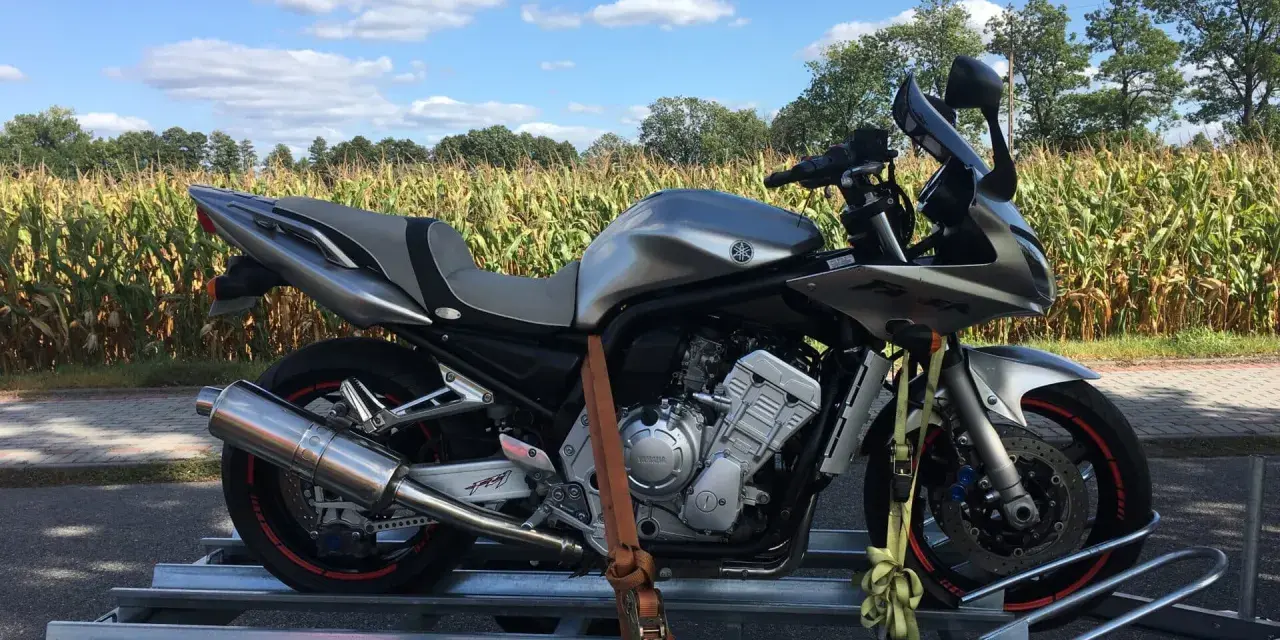 Srebrny motocykl na przyczepce, gotowy do transportu. Idealne tanie motocykle z Niemiec dla każdego fana dwóch kółek.