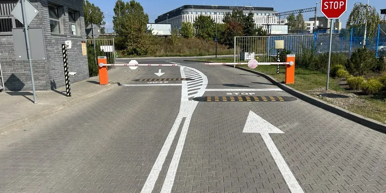 Przed wjazdem na teren hotelu Mercure widać szlabany i znaki ostrzegawcze: STOP, strzałki kierunkowe i progi zwalniające.