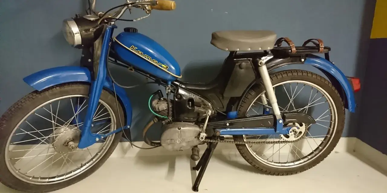 Niebieski motorower Komar, jeden z klasycznych polskich motorowerów, z charakterystycznym napisem na baku.