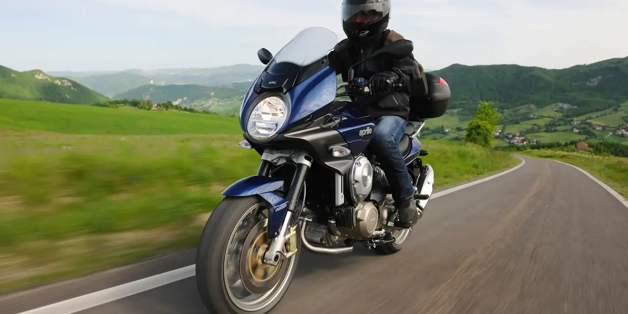 Motocykle szosowo turystyczne przemierzają malownicze, zielone wzgórza.