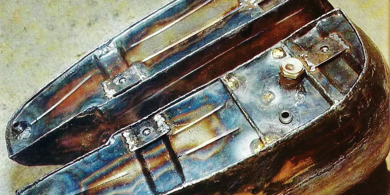 Metalowy zbiornik paliwa motocykla, gotowy do czyszczenia. Widać spawy i mocowania.