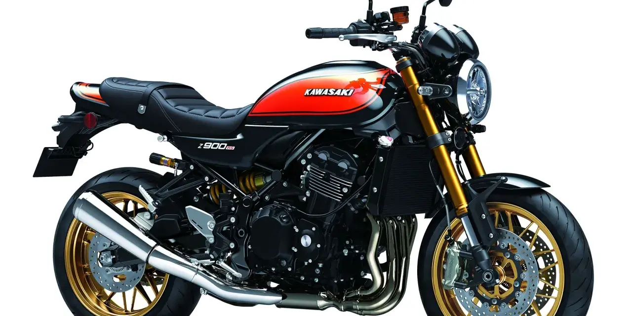 Stylowy czarny motocykl Kawasaki Z900RS z pomarańczowo-żółtym malowaniem na baku i złotymi felgami.