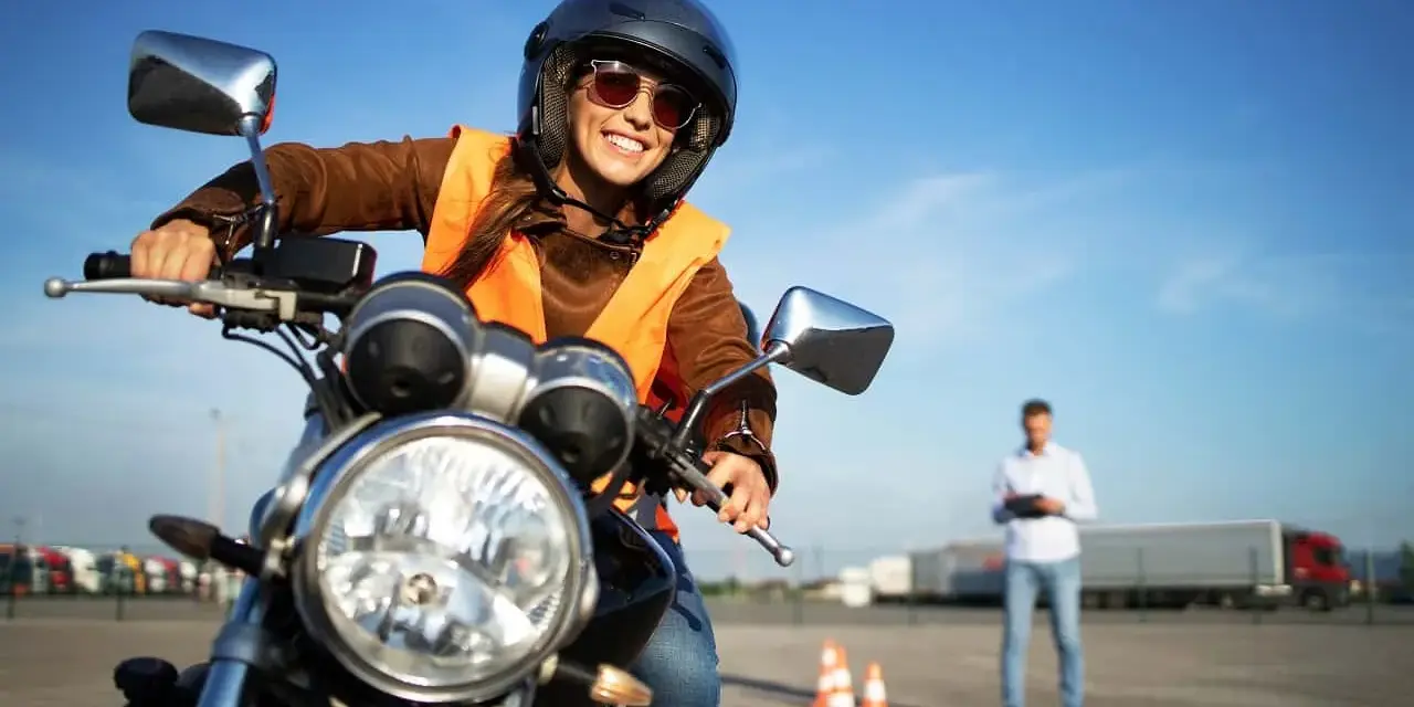 Uśmiechnięta kursantka na motorze, gotowa na egzamin. Zastanawiasz się, jakie prawo jazdy na motor 1000? To kategoria A.