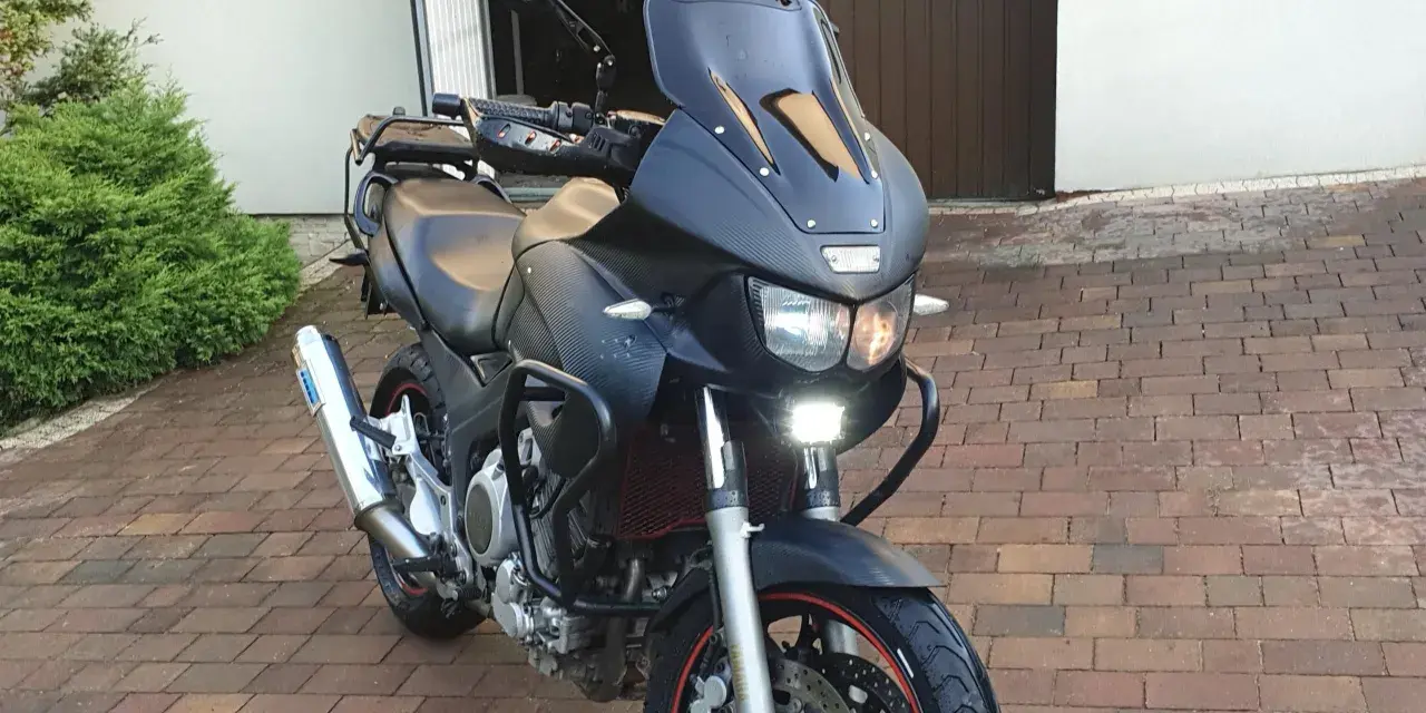 Czarny motocykl Yamaha TDM 850 z turystyczną owiewką i dodatkowymi światłami LED, gotowy na przygodę.