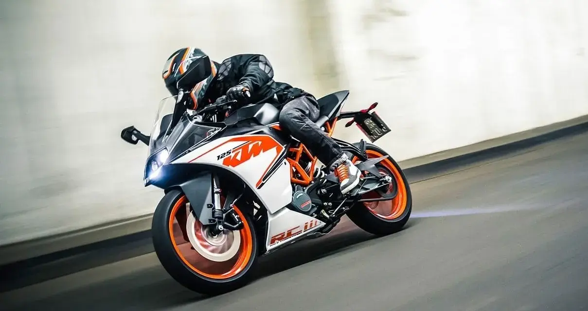 Motocyklista w kasku śmiga na KTM RC 125, osiągając maksymalną prędkość na torze.