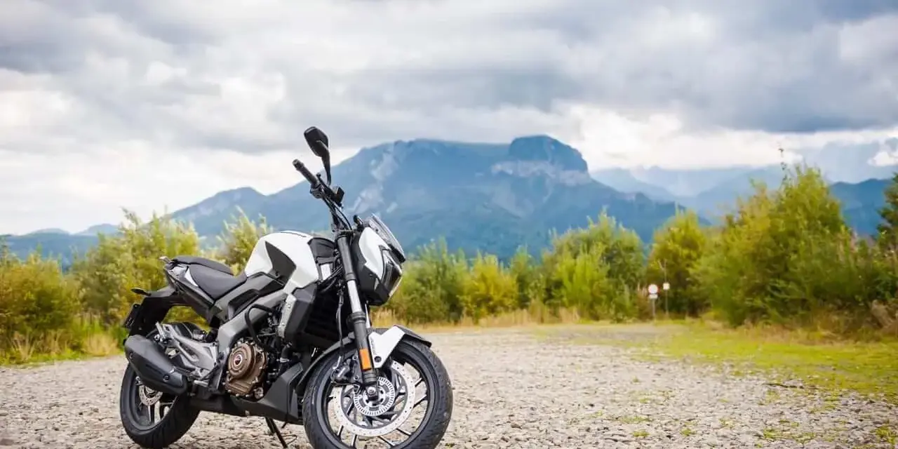 Biało-czarny Bajaj Dominar 400 na tle gór i chmur. Gotowy na przygodę w dziczy.