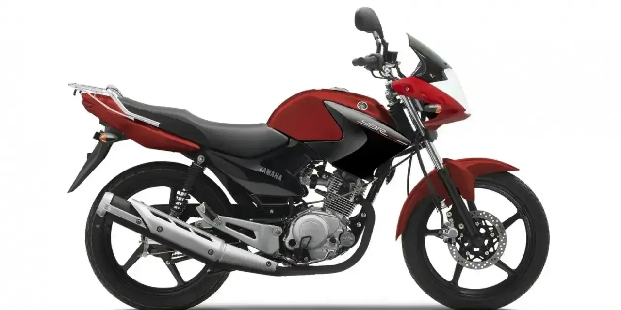 Czerwony motocykl Yamaha YBR 125, z czarnymi akcentami i bagażnikiem. Wady tego modelu to m.in. brak wskaźnika paliwa.