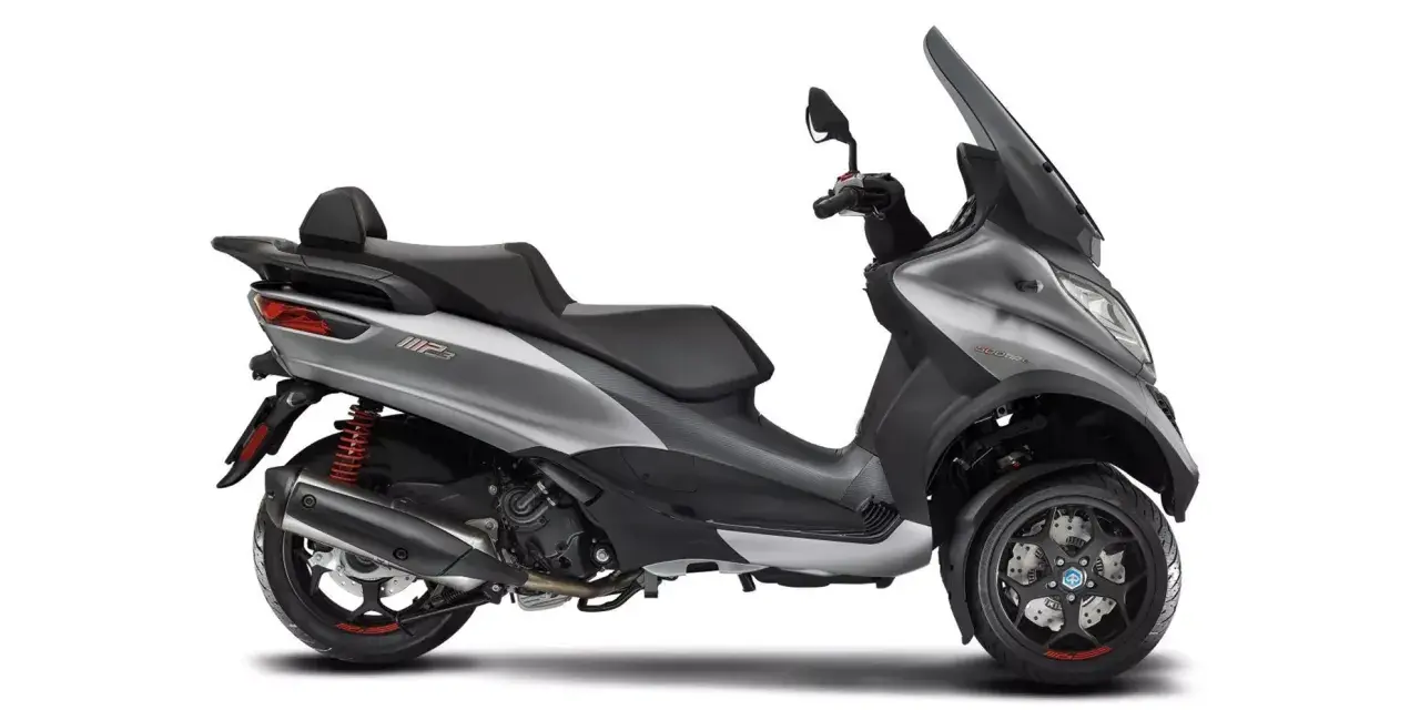 Srebrny Piaggio MP3 500, trójkołowy skuter z czarnym siedzeniem i dużą szybą. Poznaj jego piaggio mp3 500 dane techniczne.