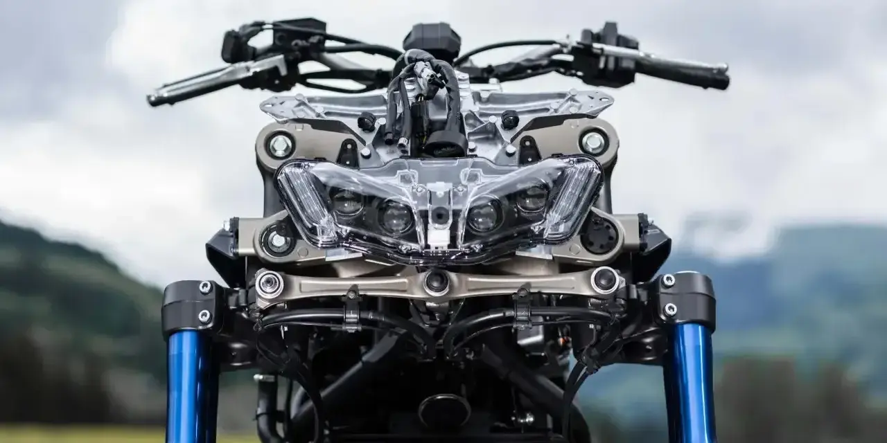 Przód motocykla Yamaha Niken GT z niebieskimi lagami i charakterystycznym, wielopunktowym reflektorem.