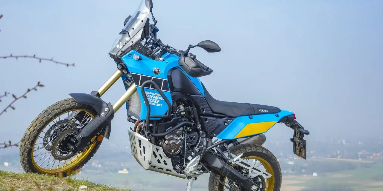 Niebiesko-żółty motocykl Yamaha Tenere 700 Rally gotowy na przygodę na wzgórzu.