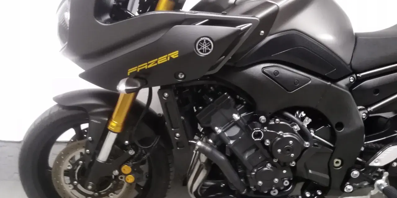 Ciemnoszary motocykl Yamaha FZ8 z żółtym napisem "FAZER" na baku. Widoczny fragment przedniego koła, zawieszenia i silnika.