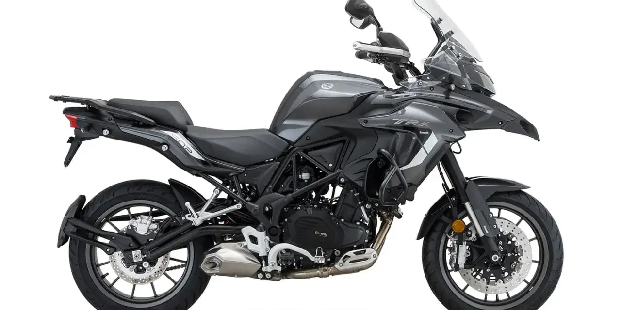Szary motocykl Benelli TRK 502 z czarnym siedzeniem i bagażnikiem, gotowy na przygodę.