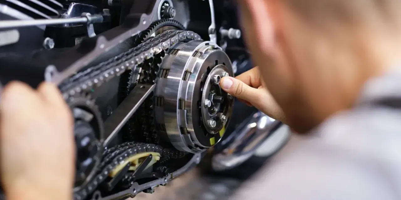 Mechanik reguluje sprzęgło, kluczowy element do nauki, jak zmieniać biegi w motocyklu 125.