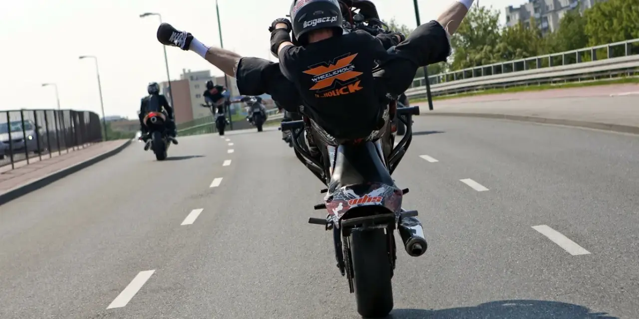 Motocyklista wykonuje jazdę na jednym kole, rozkrokiem. Ryzykowne wyczyny mogą skończyć się mandatem.