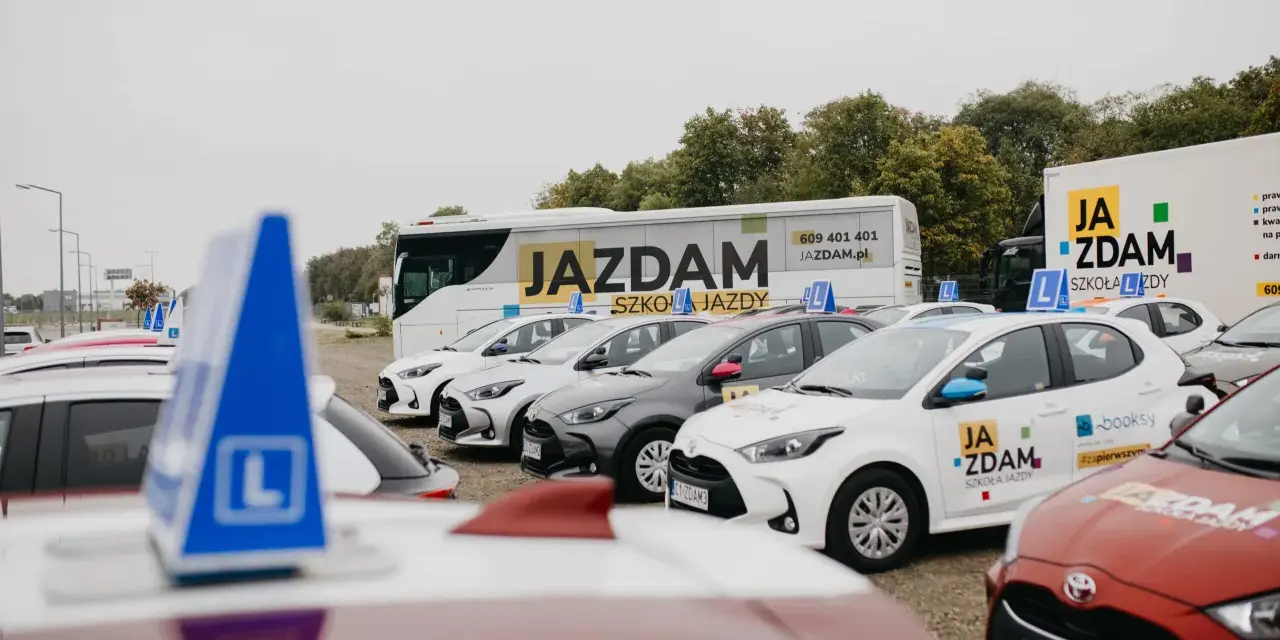 Auta szkoleniowe z literą "L" na dachu, gotowe do nauki różnych kategorii prawa jazdy.