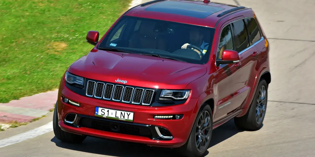 Czerwony Jeep Grand Cherokee na torze. Zastanawiasz się, ile kosztuje personalizowana rejestracja, gdy widzisz tablicę S1 LNY?