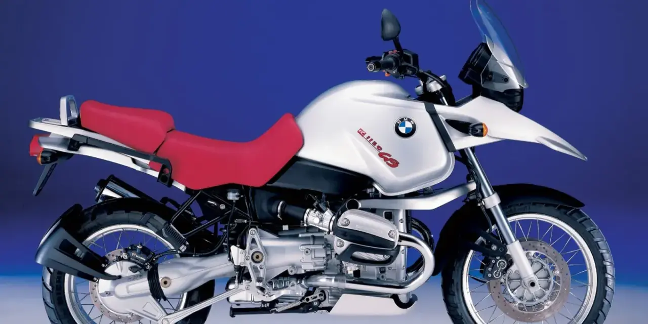 Srebrny motocykl BMW R 1150 GS z czerwoną kanapą, gotowy na przygodę.