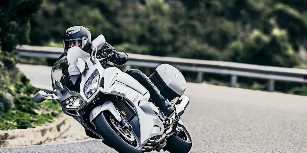 Motocyklista w kasku pochyla się na białym motocyklu Yamaha FJR 1300, pokonując zakręt. Dane techniczne tego modelu są imponujące.