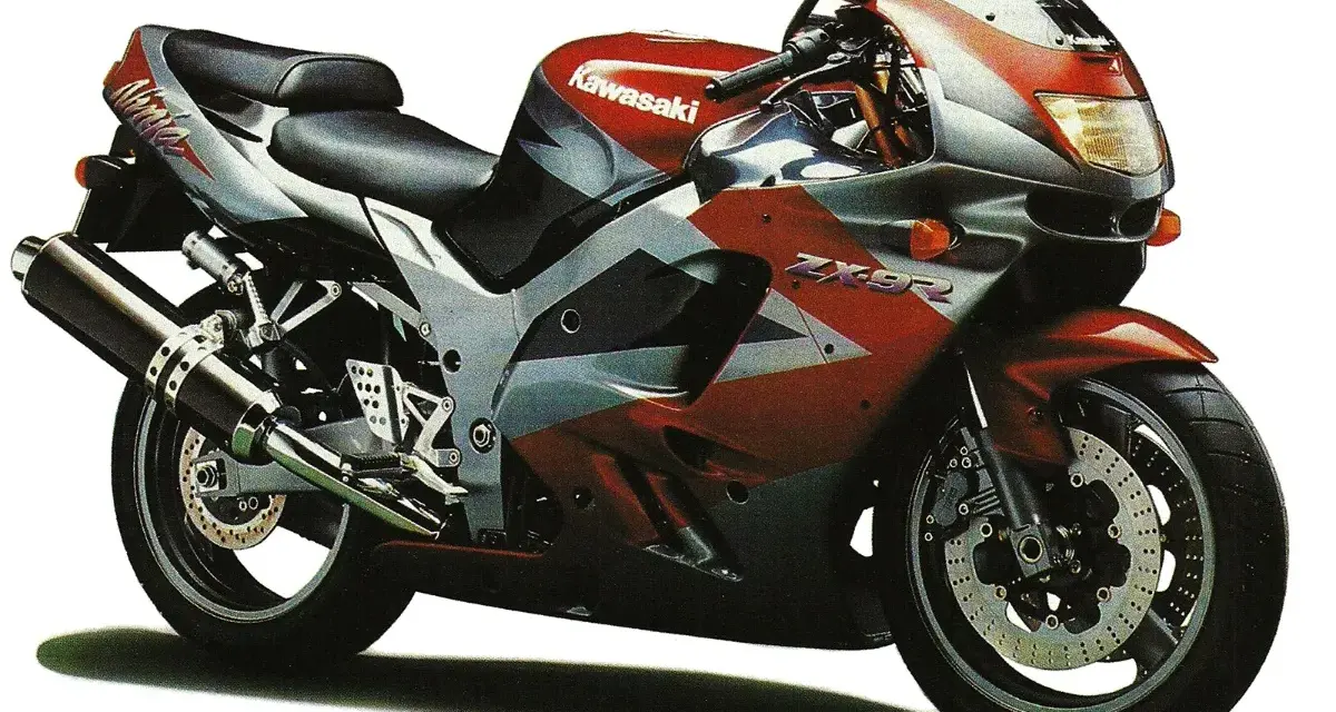 Sportowy motocykl Kawasaki ZX9R w czerwono-srebrnej kolorystyce, gotowy do jazdy.