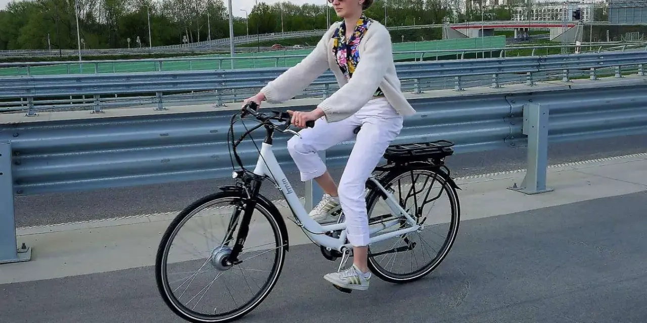 Młoda kobieta na rowerze elektrycznym, zastanawia się, czy na rower elektryczny trzeba mieć prawo jazdy.