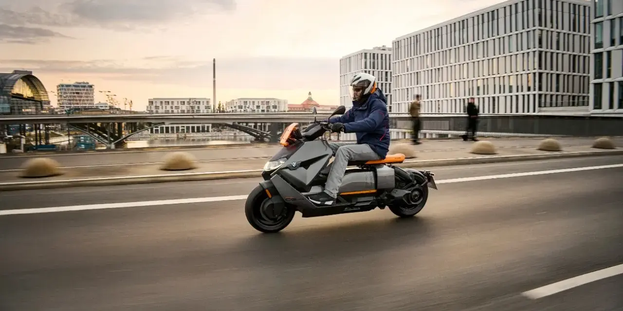 Mężczyzna w kasku jedzie na skuterze BMW CE 04 po mieście.