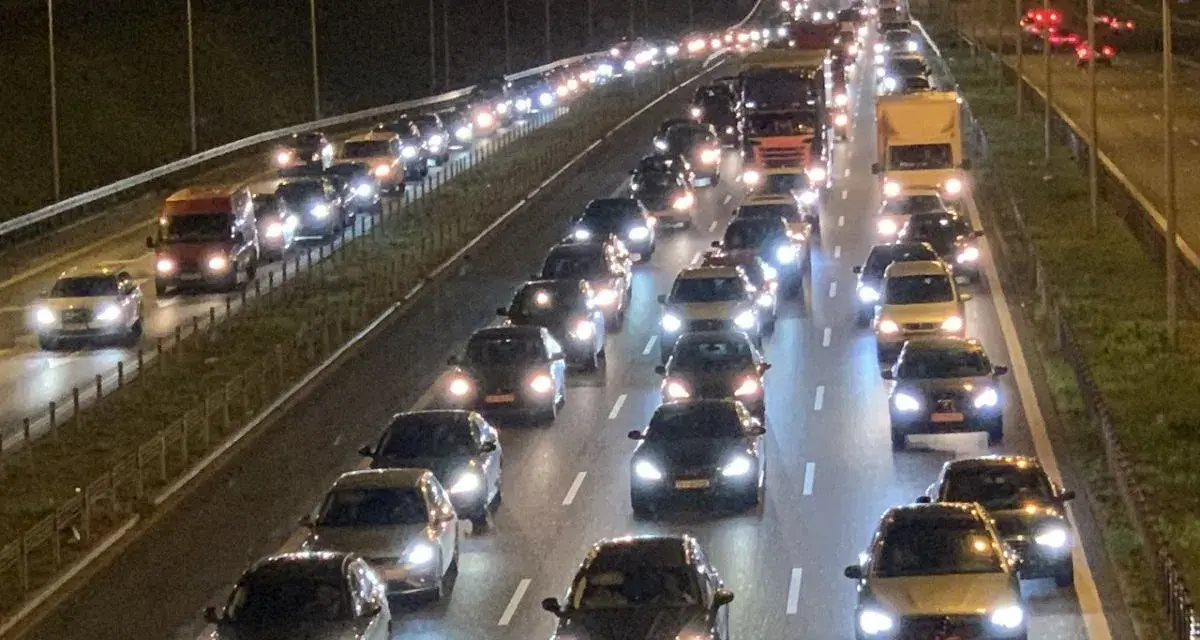 Nocny korek na drodze S8. Długi sznur samochodów i ciężarówek z zapalonymi światłami tworzy świetlisty tunel.