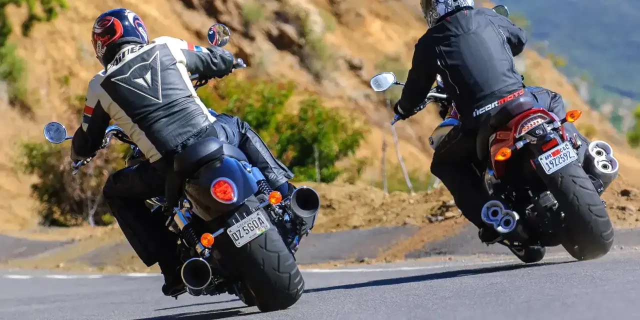 Dwóch motocyklistów na zakręcie. Jeden na Yamaha R3, drugi na V-Max, w skórzanych kombinezonach, pokonuje górską drogę.