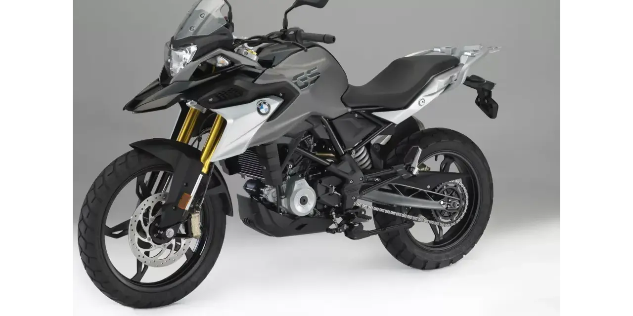 Szary motocykl BMW 310 GS z czarnym siedzeniem i złotymi amortyzatorami, gotowy na przygodę.