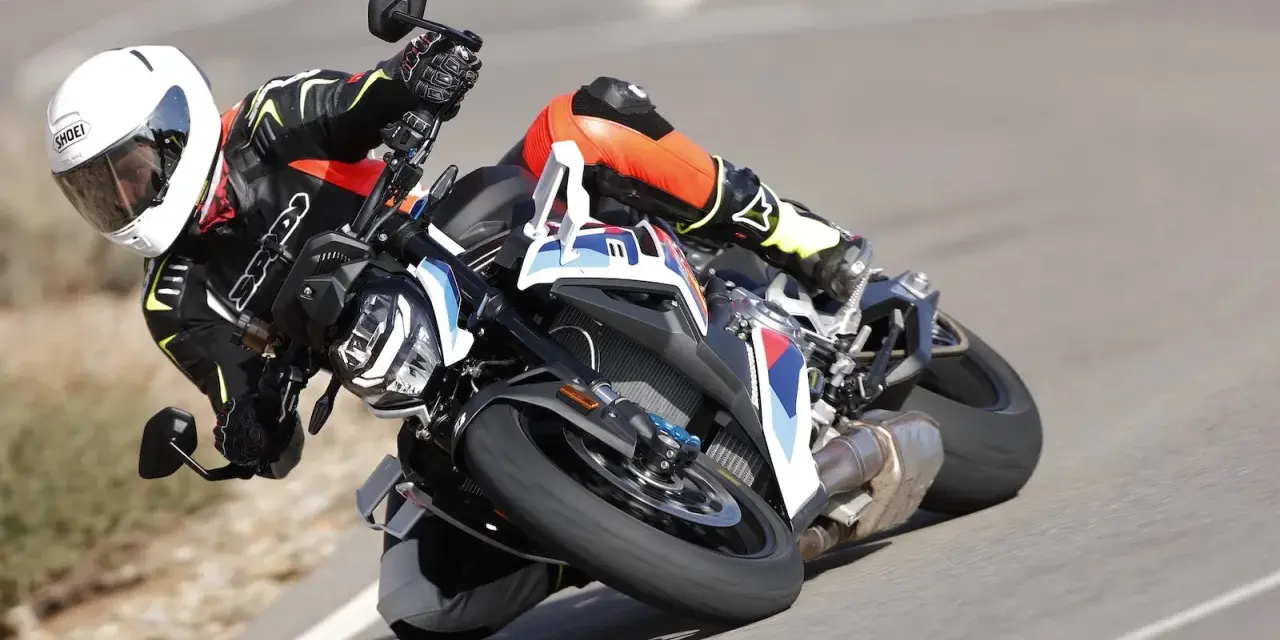 Motocyklista w kombinezonie i kasku pochyla się na zakręcie na sportowym motocyklu BMW. DTC BMW zapewnia kontrolę.