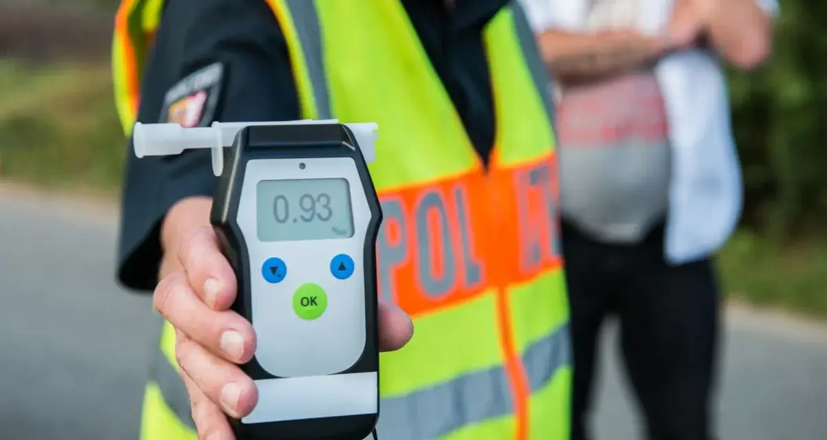 Policjant pokazuje alkomat z wynikiem 0.93 promila. To przekroczenie dopuszczalnej ilości alkoholu w wydychanym powietrzu.