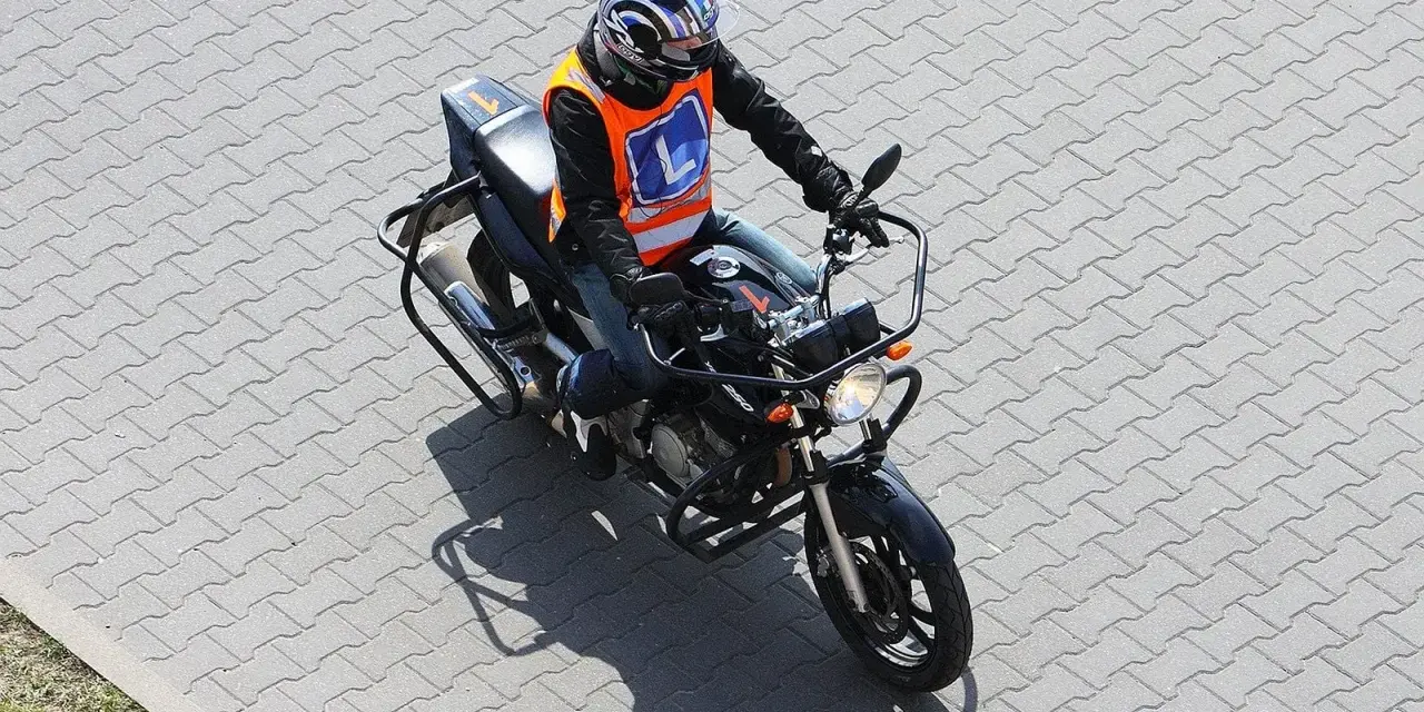 Motocyklista w kamizelce z literą "L" (kategoria A2) na placu manewrowym.