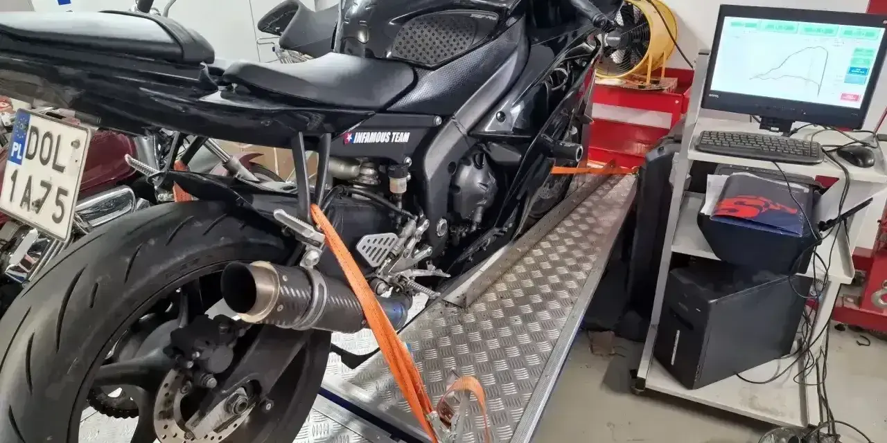 Czarny motocykl na hamowni, przygotowany do testów. Pomiar mocy i momentu obrotowego, czyli blokowanie motocykla na A2, to klucz do optymalizacji osiągów.