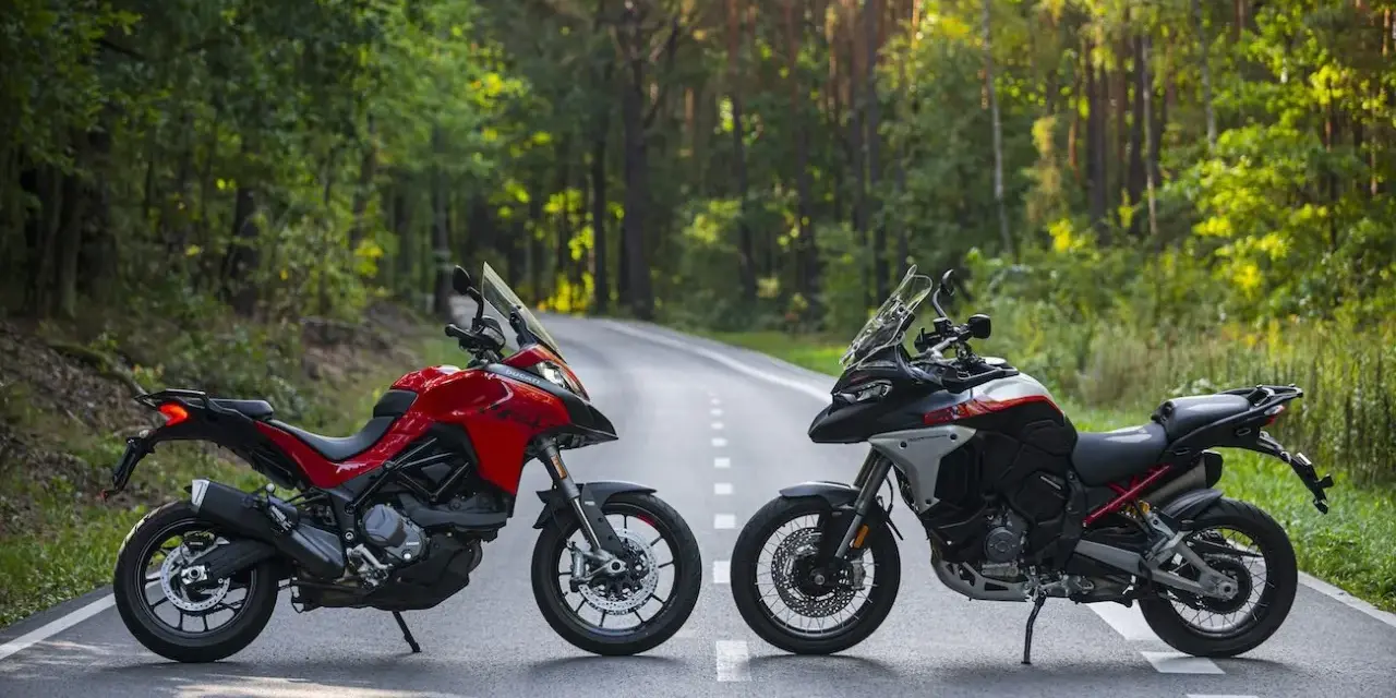 Dwa motocykle Ducati Multistrada, czerwony i czarno-biały, stoją na leśnej drodze.