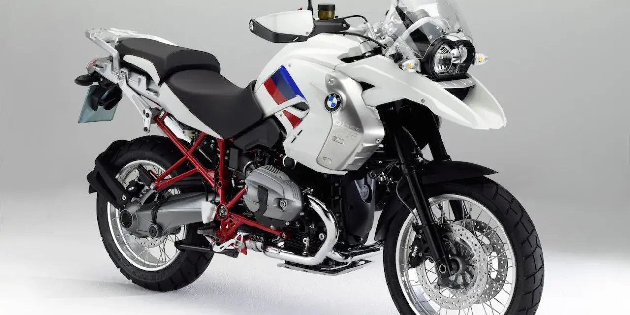 Biały motocykl BMW R1200GS z czerwonym stelażem. Czy to model olejowy, czy wodny?