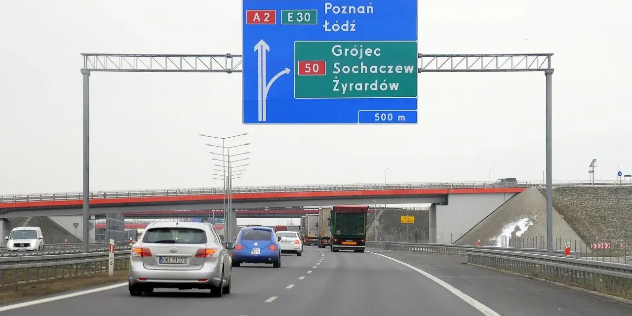 Autostradą A2 w kierunku Poznania i Łodzi. Znak informuje o minimalnej prędkości na autostradzie i zjeździe na Grójec, Sochaczew, Żyrardów za 500 m.