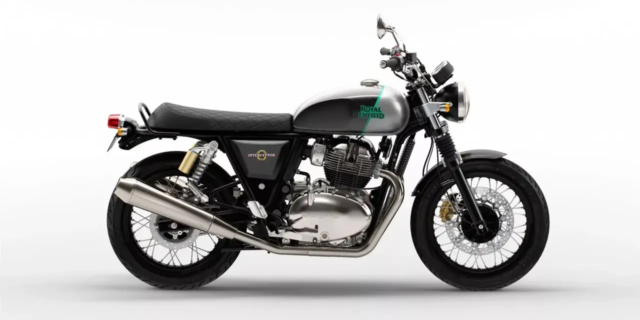 Stylowy Royal Enfield Interceptor 650 w kolorze szaro-zielonym, z chromowanym silnikiem i czarnym, pikowanym siedzeniem, gotowy na każdą podróż.