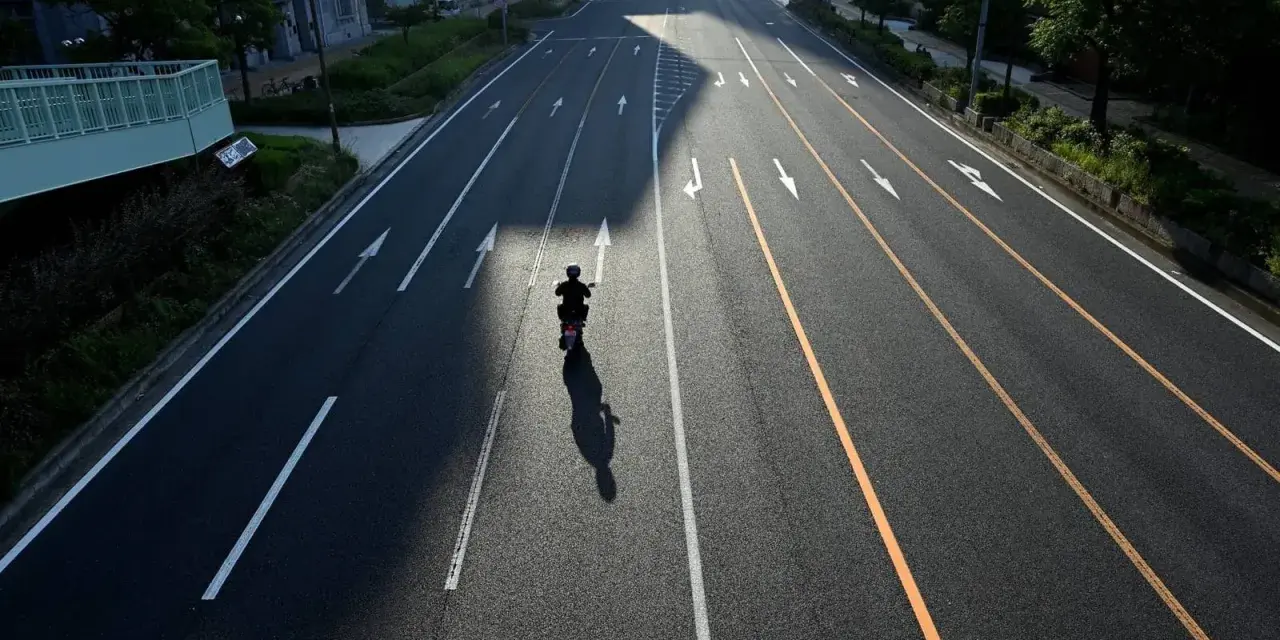 Samotny motocyklista na pustej drodze, cień rzuca się na asfalt. Zastanawia się, jak wyrejestrować skuter.